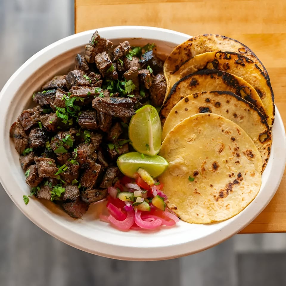 El Jefe's Grill Mexican BBQ plate with grilled steak, tortillas, lime, and pickled onions.
