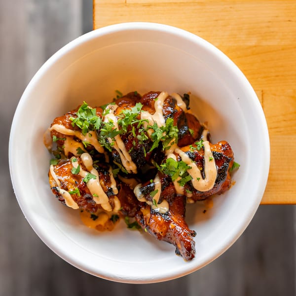 El Jefe's Grill Mexican BBQ wings, drizzled with sauce and garnished with fresh cilantro in a white bowl.